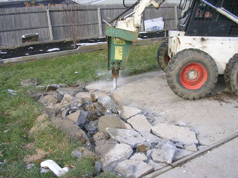 A skid steer breaking up a concrete slab